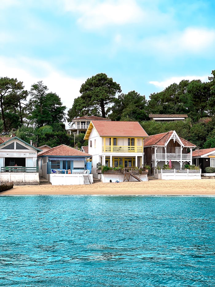 Colorful beachfront houses beside calm turquoise sea under bright sky, capturing serene coastal living.