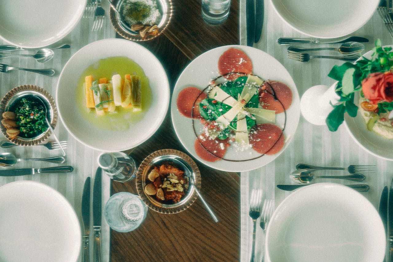 Aerial view of a finely set dining table with assorted gourmet dishes and elegant tableware.